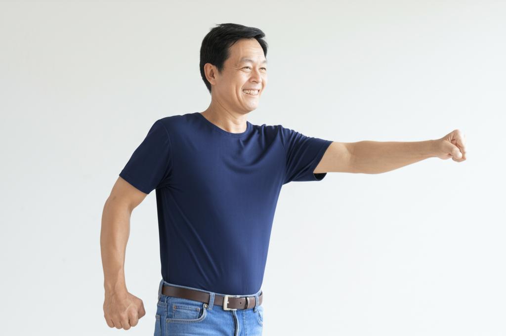 Middle-aged Asian man looking energetic and happy, perhaps walking confidently or engaging in a light activity, realistic photo